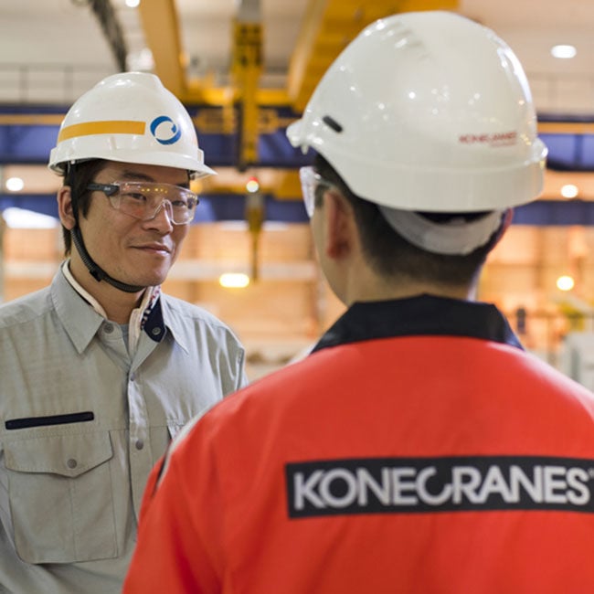 2 Konecranes workers chatting in a factory environment.