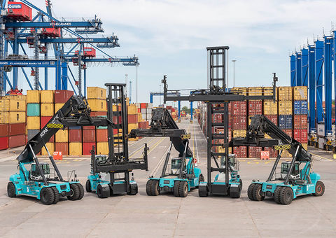 Three Konecranes reachstackers and two container handlers in a row, facing the camera, at a container terminal.