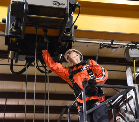 Service technician inspecting a crane in a factory