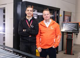 Agilon warehouse automation experts standing next to automated storage equipment with an Autoload Trolley and conveyor system.